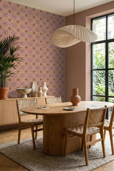 Tapete mit geometrischem Muster im hellen Esszimmer mit ovalem Holztisch, geflochtenen Stühlen und moderner Hängeleuchte vor einem Fenster.