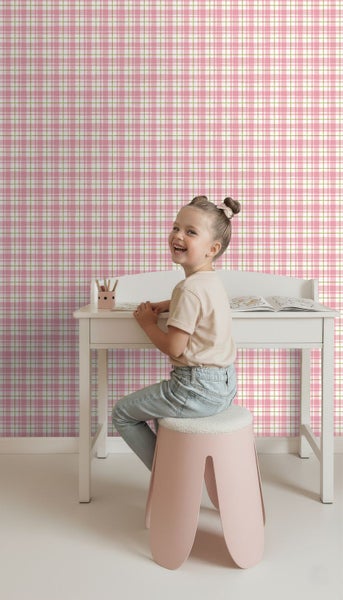 Zimmer mit rosafarbener Karotapete, weißem Schreibtisch und Kind