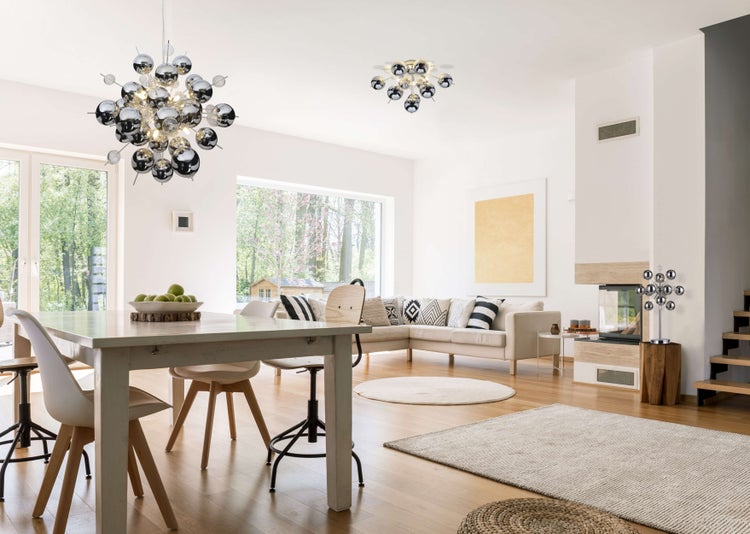 Heller Wohnraum mit Esstisch, Sofa und moderner Beleuchtung