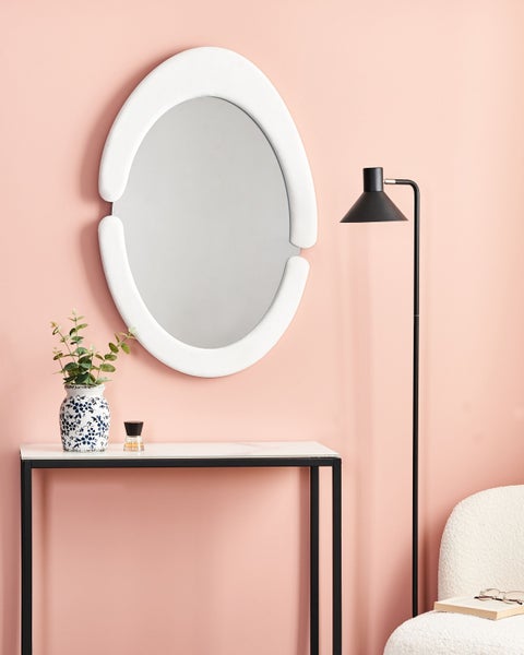 Dekoratives Interieur mit Spiegel, Konsole, Stehlampe und Sessel.