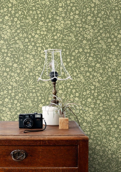 Dekoratives Zimmer mit geblümter Tapete, Vintage-Tisch und Lampe