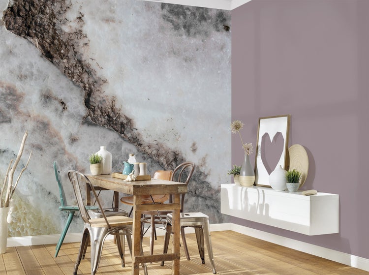 Fototapete in Marmoroptik an einer Wand in einem modern eingerichteten Esszimmer mit Holztisch und Metallstühlen.