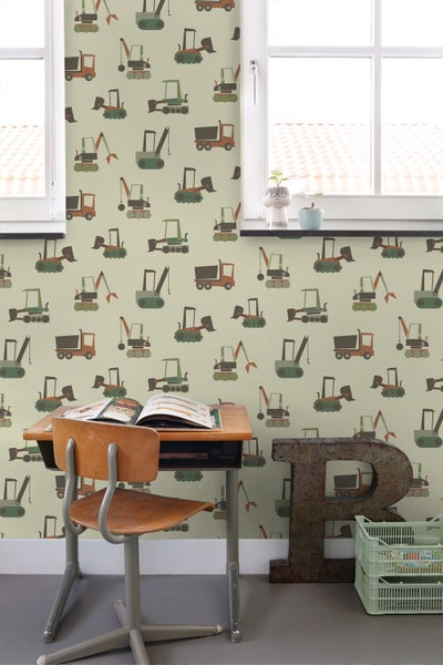 Tapete mit Baustellenfahrzeugen in einem hellen Kinderzimmer mit Schreibtisch aus Holz, Stuhl und großem Buchstaben R.