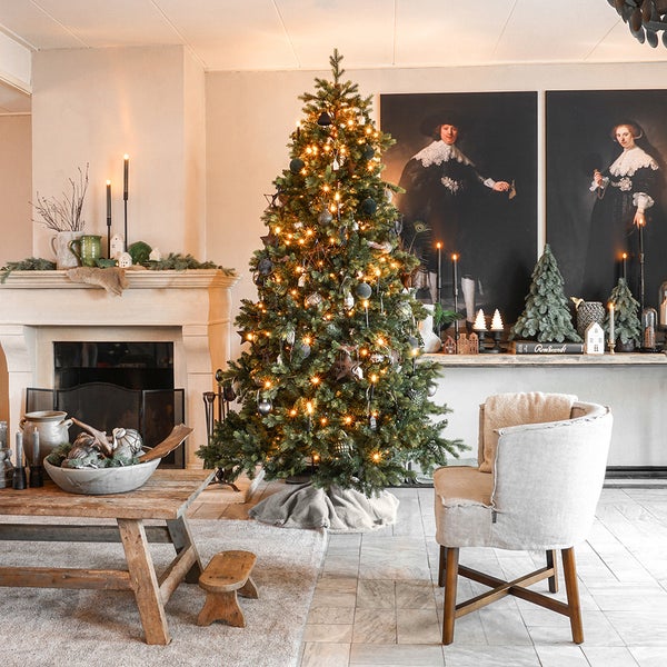 Weihnachtlich dekorierter Wohnraum mit Weihnachtsbaum, Kamin und Sitzgelegenheit
