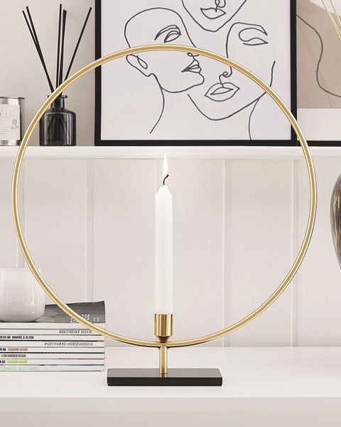 Dekorative Kerze mit Kerzenhalter in Ringform auf einem Regal