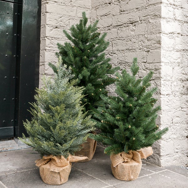 Gruppe von künstlichen Weihnachtsbäumen in Jutesäcken