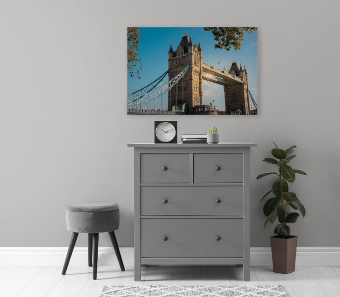 Wandbild mit Motiv der Tower Bridge in London über einer modernen Kommode mit Hocker und Pflanze in einem elegant eingerichteten Wohnraum