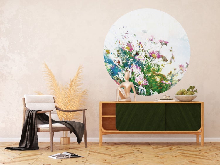 Wohnzimmer mit Sessel, Kommode und runder Blumendekoration an der Wand.