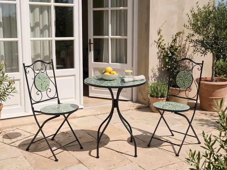 Dreiteiliges Bistro-Set mit Mosaiktisch und Metallstühlen im mediterranen Stil auf einer hellen, organisierten Steinterrasse.