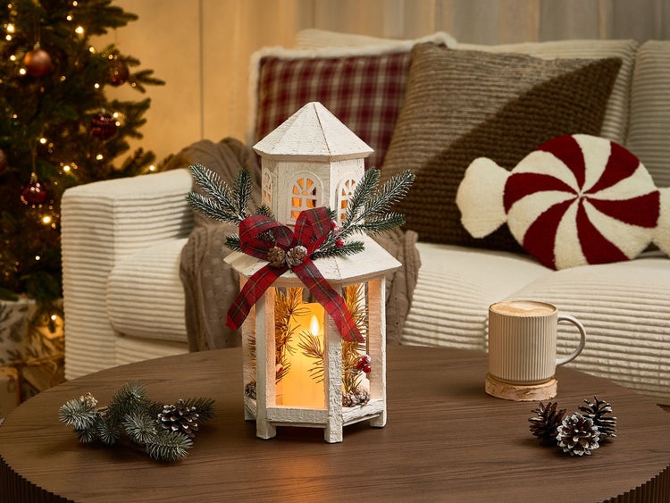 Dekoratives Wohnambiente mit Laterne, Tasse und Weihnachtsbaum im Hintergrund