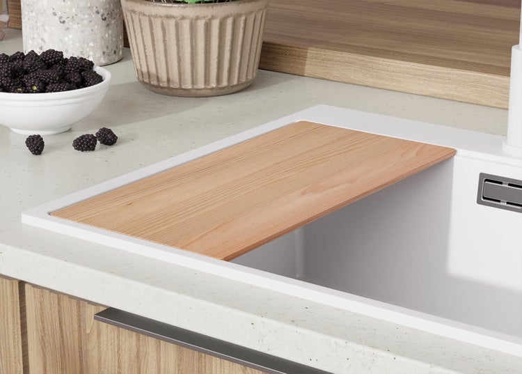 Spüle mit Schneidebrett, Schale mit Brombeeren und Topfpflanze auf einer Küchentheke.