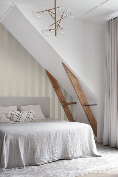 Helles Schlafzimmer mit Bett, Dachschrägen und moderner Beleuchtung