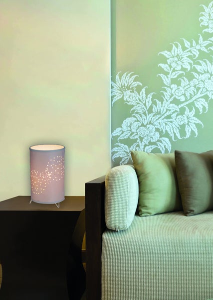 Dekorative Tischlampe auf Nachttisch neben Sofa in hellem Raum.