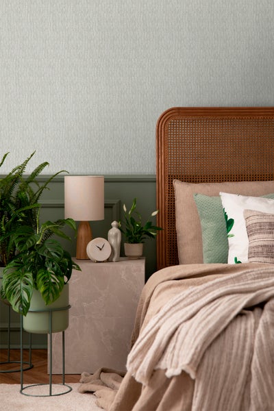 Schlafzimmer mit Bett, Nachttisch und Zimmerpflanzen