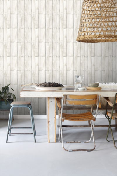 Heller Raum mit Holzwandtapete, Esstisch, Stühlen und Korbleuchte.