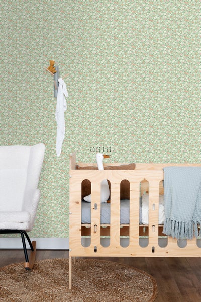 Ein Kinderzimmer mit einer floralen Tapete, einem Holzbabybett und einem Schaukelstuhl.