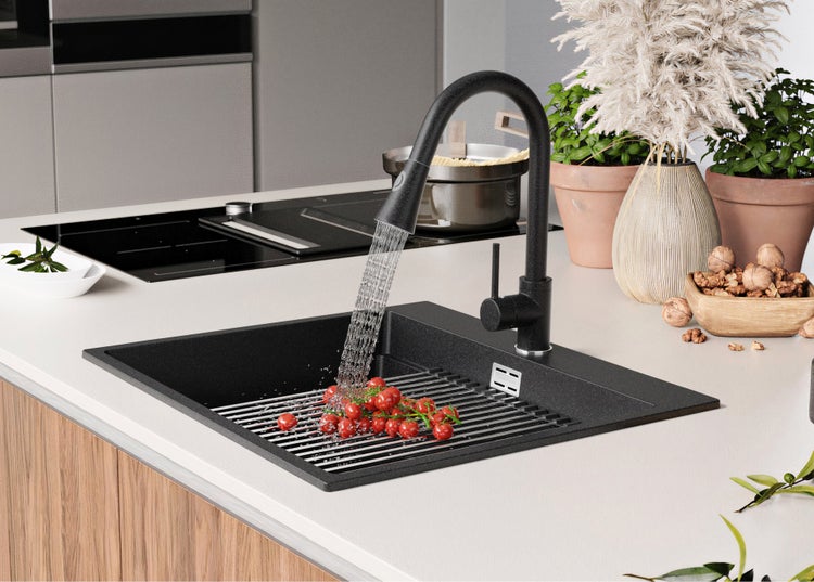 Schwarze Küchenspüle mit Armatur, Abtropfgitter und Tomaten