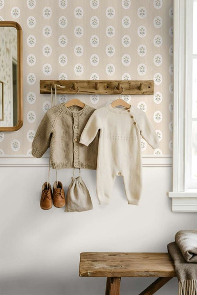 Wohnraum mit gemusterter Tapete mit Blumenmotiv, Holzgarderobe, Kinderkleidung und einer rustikalen Holzbank im hellen und freundlichen Ambiente.