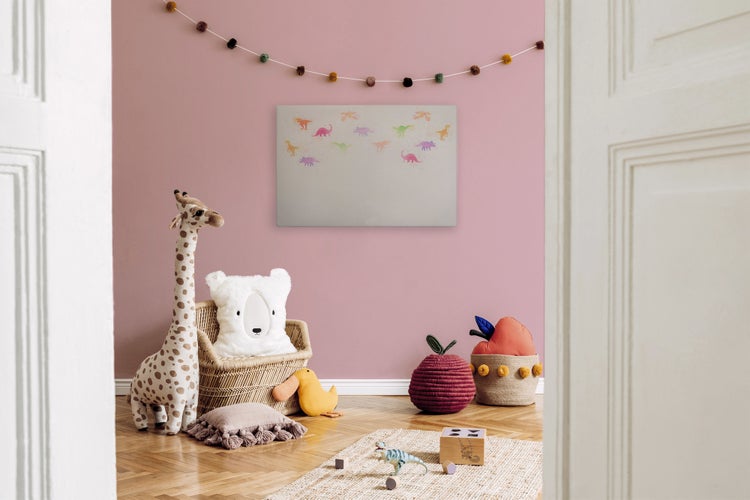 Wandbild mit Dinosauriermotiv in einem liebevoll eingerichteten Kinderzimmer mit Stofftieren und Rattansessel.