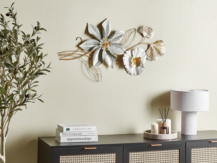 Dekoratives Wandbild mit Blumen und Blättern aus Metall über einem Sideboard.