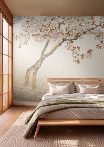 Schlafzimmer mit Fototapete mit Baum und Blüten, Bett mit Kissen und Decke.
