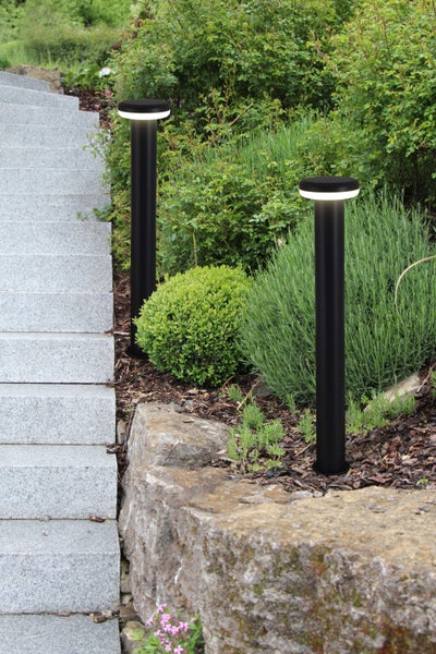 Zwei schwarze Wegeleuchten beleuchten einen Gartenweg mit Steinstufen.