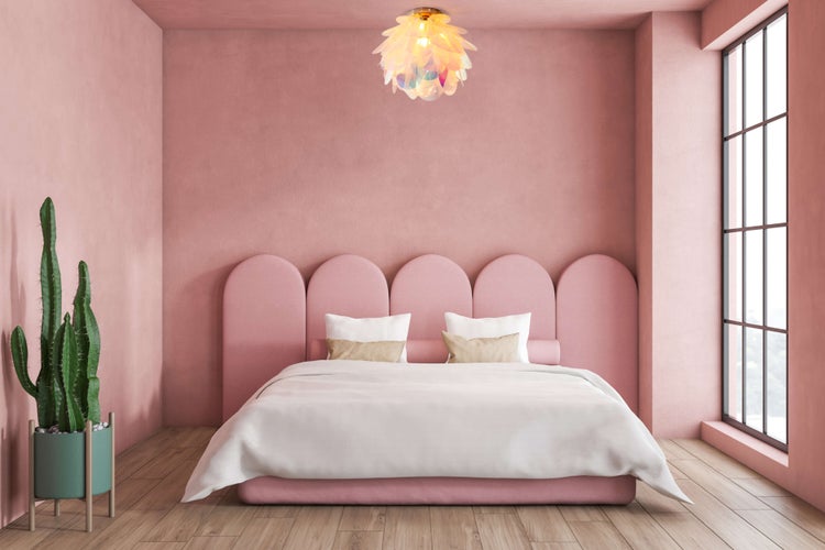 Helles Schlafzimmer mit Doppelbett, Nachttischlampe und Kaktus