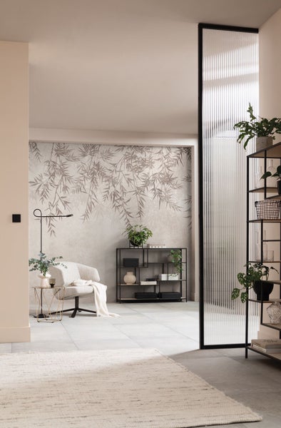 Wohnzimmer mit Sessel, Regal und Bambusmuster Tapete für eine helle und organisierte Atmosphäre.