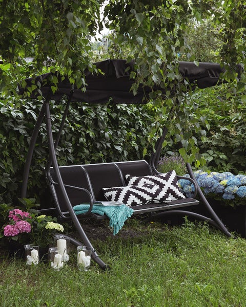 Gartenschaukel mit Kissen und Dekoration im Garten