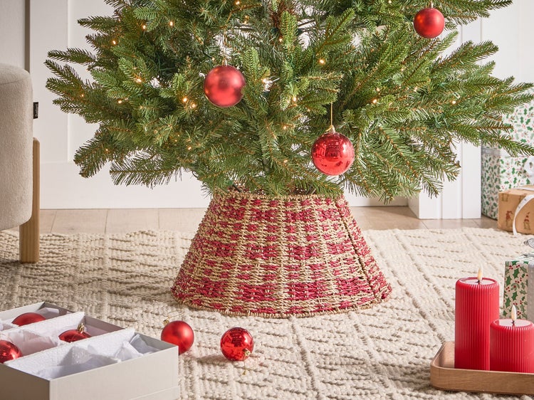 Weihnachtsbaum mit Baumschmuck, geflochtener Baumständer und Geschenken