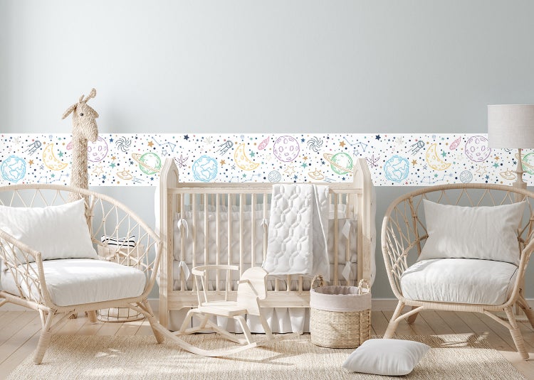 Wandbordüre für Kinderzimmer mit Weltraum-Motiven wie Planeten und Sternen in einem hellen Babyzimmer mit Gitterbett aus Holz.