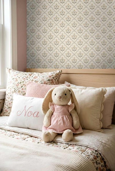 Vliestapete mit floralem Muster in Gitteroptik in einem hellen Kinderzimmer mit Bett, Kissen und Stoffhase.