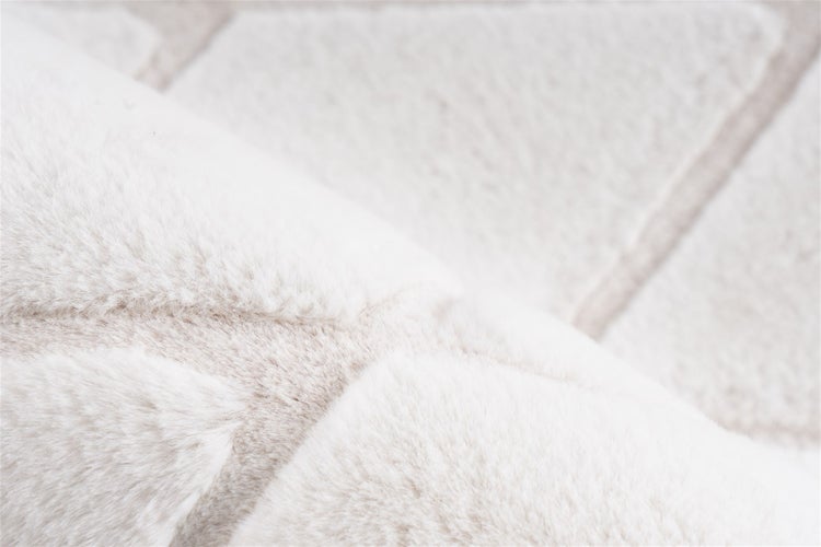 Detailaufnahme eines flauschigen Hochflor-Teppichs mit weicher Webpelz-Struktur und dezentem geometrischem Muster.