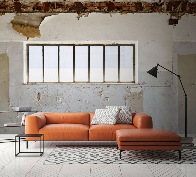 Wohnzimmer mit Sofa, Hocker, Teppich, Tisch, Regal und Stehlampe vor einer Wand mit abblätterndem Putz