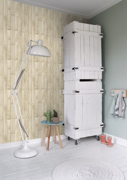 Heller Raum mit einer Wandtapete im Holzdesign, einer weißen Stehlampe, einem weißen Schrank auf Rollen und einem kleinen Beistelltisch