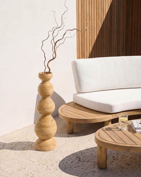 Moderne Terrassengestaltung mit geschwungenem Holzsofa, weißen Polstern, passendem Couchtisch und einer hohen Rattan-Boden-Vase.