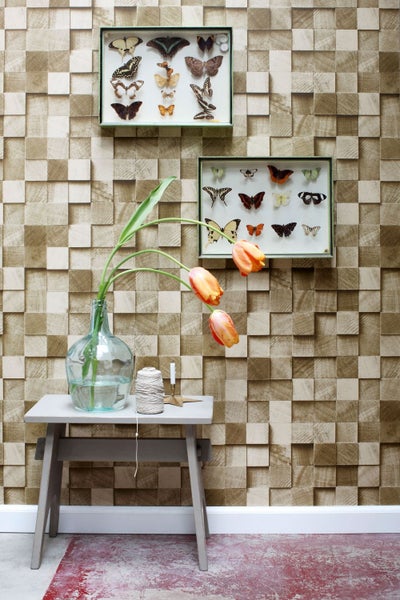 Dekoratives Zimmer mit einer dreidimensionalen Holzblocktapete, zwei Schaukästen mit Schmetterlingen und einem Tisch mit einer Blumenvase.