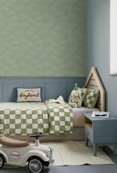Kinderzimmer mit grüner Tapete mit weißem Wolkenmuster aus Punkten, blaugrauer Wandtäfelung und einem hölzernen Hausbett.