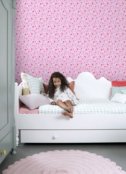 Kinderzimmer mit rosa Blumentapete, weißem Bett und Mädchen