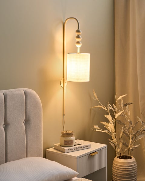 Szene eines Schlafzimmers mit Wandleuchte, Nachttisch und Dekorationsartikeln.