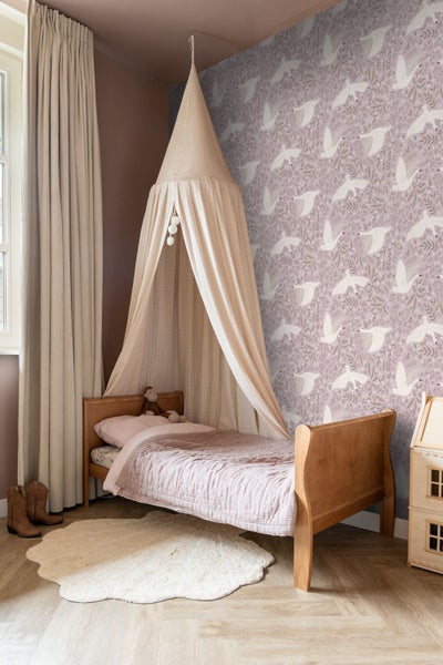 Kinderzimmer mit Schwanen-Mustertapete, Holzbett mit Betthimmel, hellem Teppich und Holzfußboden.