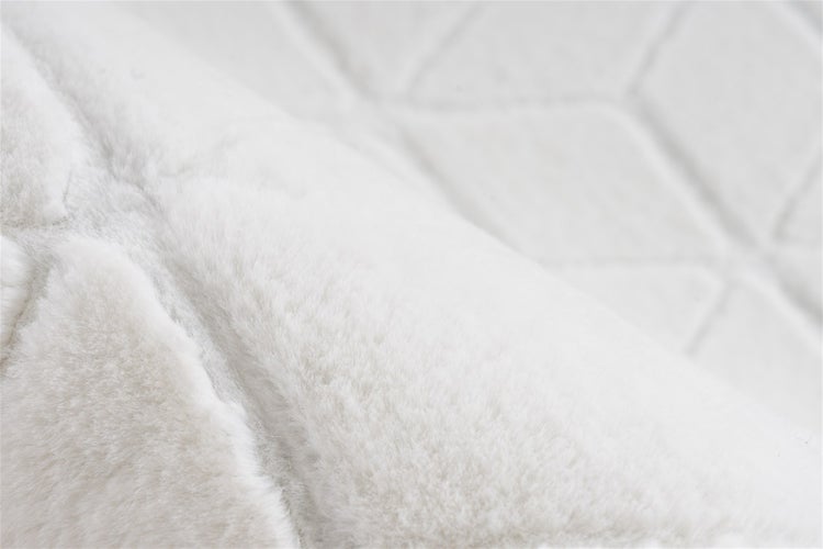 Nahaufnahme eines weichen, weißen Textilstoffs mit geometrischem Rautenmuster und flauschiger Oberfläche.