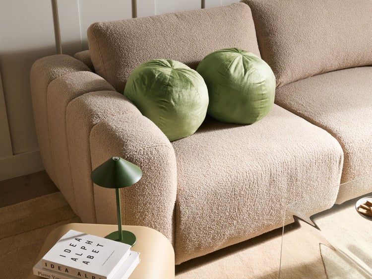 Beiges Sofa mit zwei grünen Kissen und einer Lampe