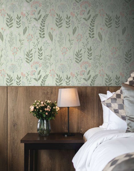 Schlafzimmer mit blumiger Vliestapete, Holzpaneelen, Nachttisch, Lampe und Blumenstrauß in einer gemütlichen und modernen Wohnatmosphäre.