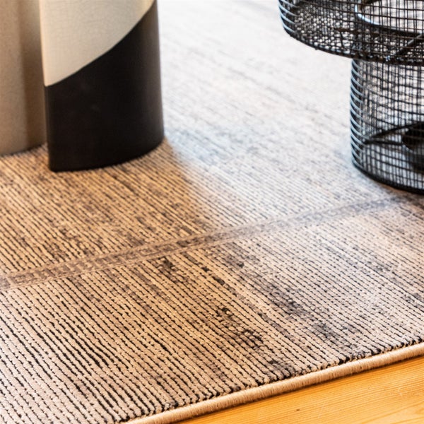 Teppich mit strukturierter, gerippter Oberfläche und linearem Muster in Grau und Beige auf Holzfußboden.