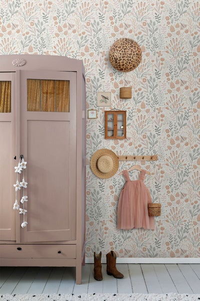 Vliestapete mit floralem Muster aus Blumen und Blättern in einem hellen Kinderzimmer neben einem Schrank im Landhausstil und einer Garderobe.