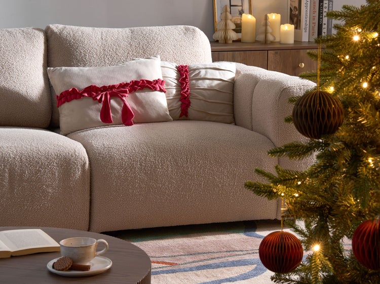 Dekoratives Wohnzimmer mit Sofa, Kissen und Weihnachtsbaum für eine festliche Atmosphäre