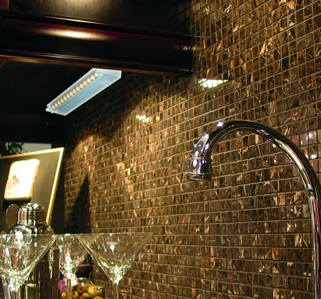 Barbereich mit Mosaikwand, Unterbauleuchte, Armatur und Cocktailgläsern.