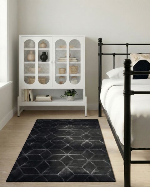 Schlafzimmer mit schwarzem Teppich mit geometrischem Muster, Bett und Vitrine