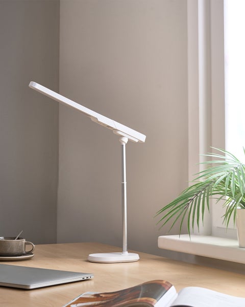 Schreibtisch mit LED-Tischleuchte, Laptop und Zimmerpflanze für eine helle Arbeitsatmosphäre